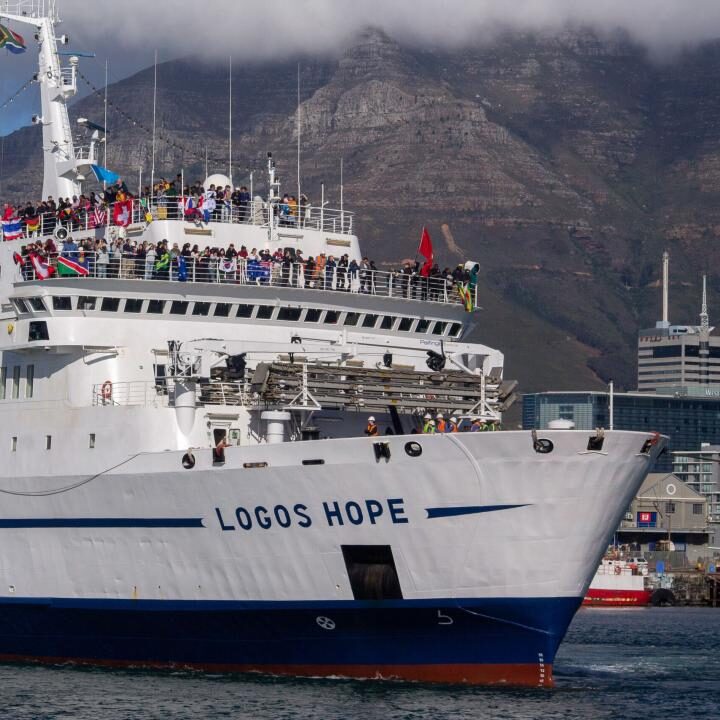A picture of a large ship called the Logos Hope showing many people on board with flags from lots of different countries